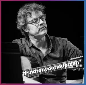 Jan luistert, gitaar in de hand.